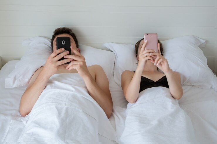 people are lying in bed with phones in their hands